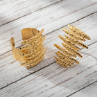 Matching hammered gold statement cuff bracelet and oversized sculptural Ring displayed together as a coordinated jewelry set.