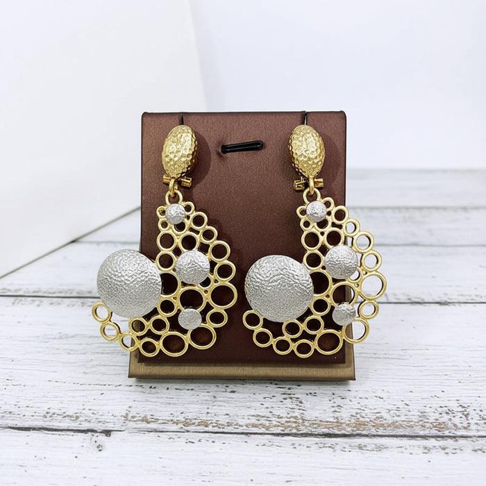 Gold and silver-tone geometric bubble earrings displayed together, featuring textured circular accents and an artistic sculptural design.