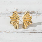 Oversized textured 18K gold flower statement earrings inspired by the Ginkgo leaf, displayed in hand to showcase the sculptural botanical design.