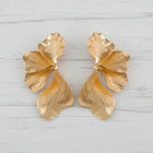 Pair of oversized 18K gold orchid statement earrings with sculptural floral petals and textured botanical design on a white background.