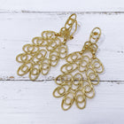 18K gold plated hollow African brass statement earrings featuring an intricate openwork filigree design displayed on a white wooden background.