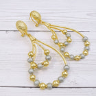 A pair of gold-tone drop earrings featuring a teardrop-shaped frame constructed from multiple thin wires. Two-tone gold and silver African-inspired geometric drop earrings featuring elegant openwork loops and lightweight statement styling.