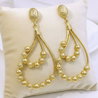 18K gold plated African geometric statement earrings with intricate sculptural openwork design displayed on a white wooden background.