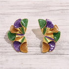 Purple, green, and gold geometric ruffle statement stud earrings with glitter enamel finish displayed on a white wooden background.