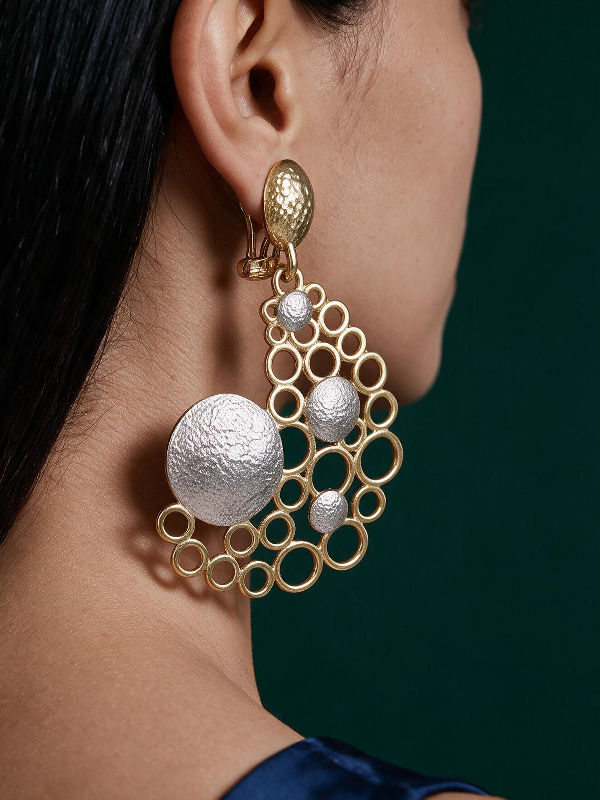 Model wearing oversized 18K gold plated bubble statement earrings featuring an open geometric circle design with textured Gold and silver-tone accents