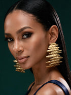 Front portrait of a model wearing bold 18K gold-plated sculptural earrings inspired by African artistry and modern luxury fashion.