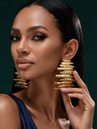 Front portrait of a model wearing bold 18K gold-plated sculptural earrings inspired by African artistry and modern luxury fashion.