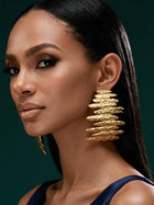 Front portrait of a model wearing bold 18K gold-plated sculptural earrings inspired by African artistry and modern luxury fashion.