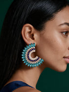 Oversized turquoise blue crystal statement earrings with gold detailing, luxury geometric rhinestone studs worn by model.