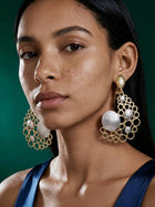 Model wearing oversized 18K gold plated bubble statement earrings featuring an open geometric circle design with textured gold accents.