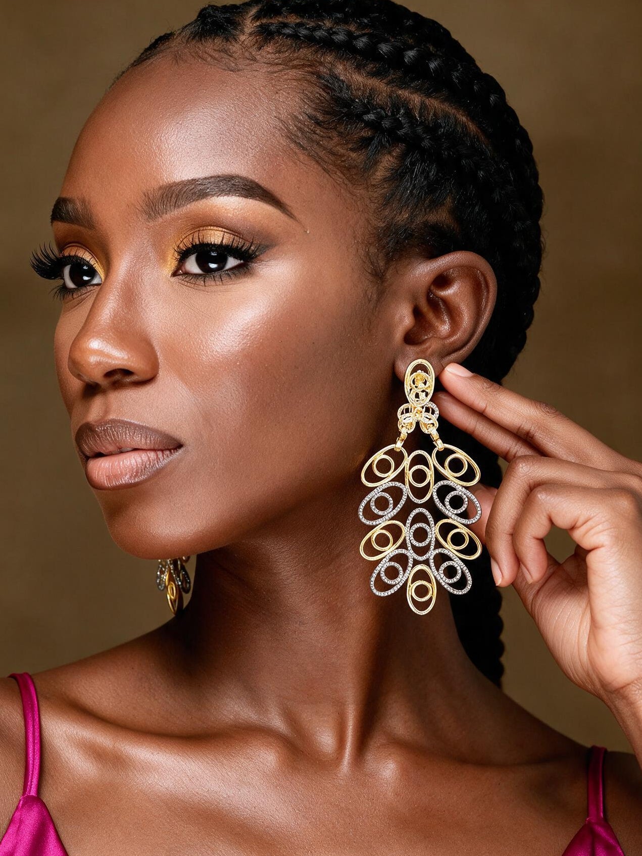 Front portrait of a woman wearing large Afrocentric hollow brass gold and silver dangle  earrings with intricate geometric loops and luxurious gold detailing.