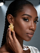 Model wearing oversized sterling silver botanical statement earrings with a sculptural Ginkgo-inspired fan design for a modern luxury look.