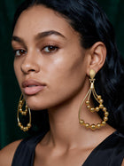 Portrait of a model wearing bold 18K gold plated African statement earrings showcasing elegant movement and lightweight luxury design.
