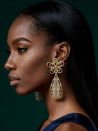 Side profile showcasing elegant African-inspired gold drop earrings with intricate openwork teardrop silhouette.