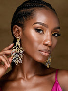 Front portrait of a woman wearing large Afrocentric hollow brass gold and silver dangle  earrings with intricate geometric loops and luxurious gold detailing.