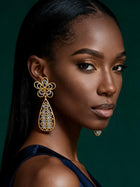 Side profile showcasing elegant African-inspired gold drop earrings with intricate openwork teardrop silhouette.