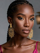 Front portrait of a woman wearing large Afrocentric hollow brass earrings with intricate geometric loops and luxurious gold detailing.