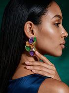 Model wearing vibrant Mardi Gras-inspired statement earrings featuring layered geometric shapes in purple, green, and gold for festival styling.