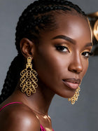 Side profile of a model wearing oversized 18K gold plated African brass filigree earrings with an elegant hollow statement design.