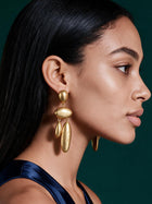 Side profile highlighting modern organic gold dangle earrings paired with sleek evening styling and braided hairstyle.