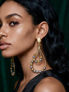 Close-up of long geometric gold drop earrings inspired by African artistry, styled with a satin dress for a modern luxury loo