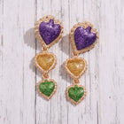 Purple, green, and gold floral statement earrings with glitter enamel petals and lightweight geometric design on a white background.