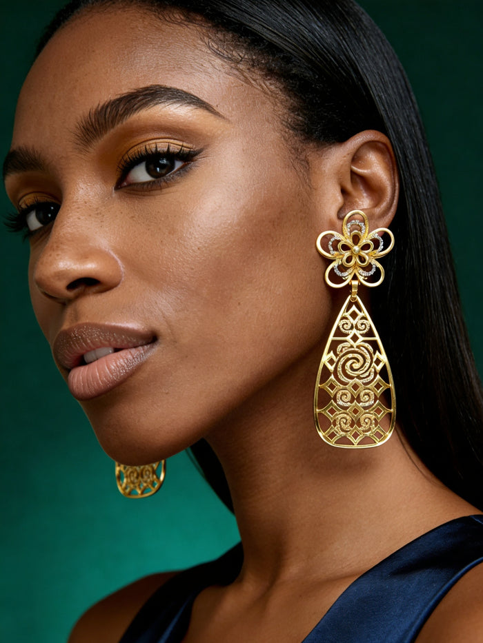 Close-up of lightweight gold filigree statement earrings with floral stud detailing and modern Afro-luxe styling.