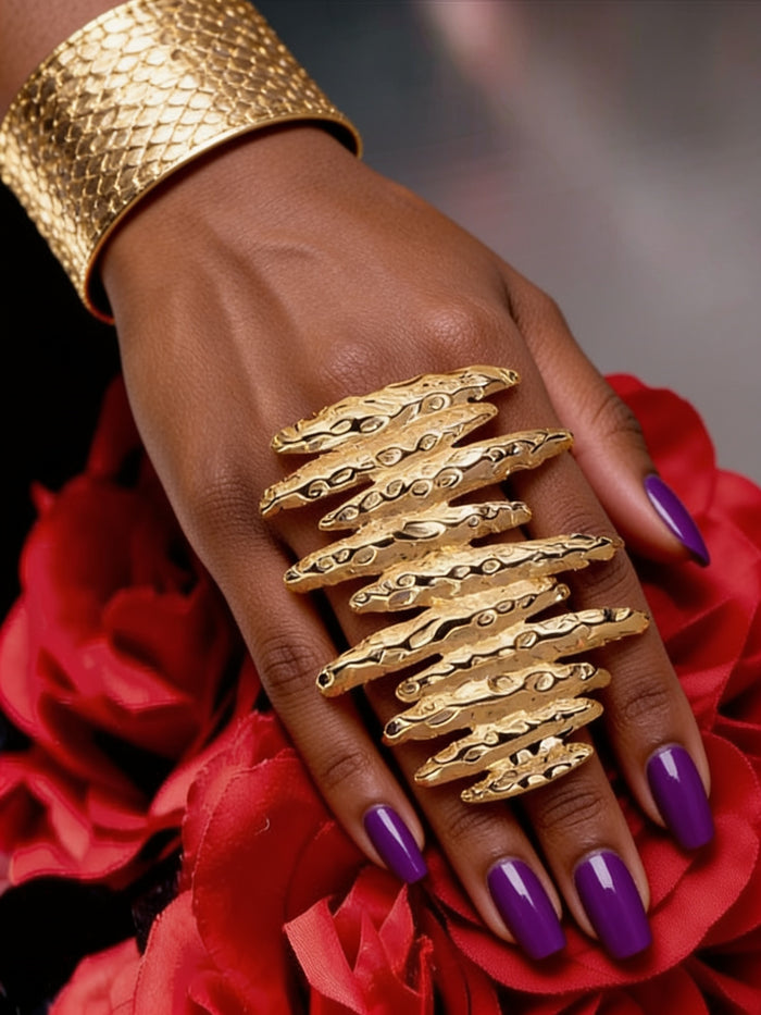 Model wearing coordinating sculptural gold bracelet and oversized statement ring featuring organic layered hammered textures and bold contemporary design.