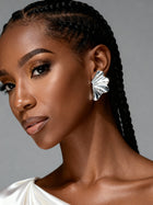 Sterling silver sculptural flower statement earrings held in hand, featuring a textured botanical leaf design and lightweight oversized silhouette.
