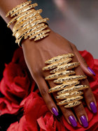 Model wearing coordinating sculptural gold bracelet and oversized statement ring featuring organic layered hammered textures and bold contemporary design.