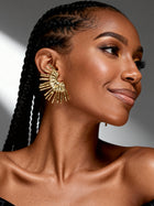 Close side profile of model wearing lightweight gold sunburst statement earrings featuring a modern sculptural fan silhouette.