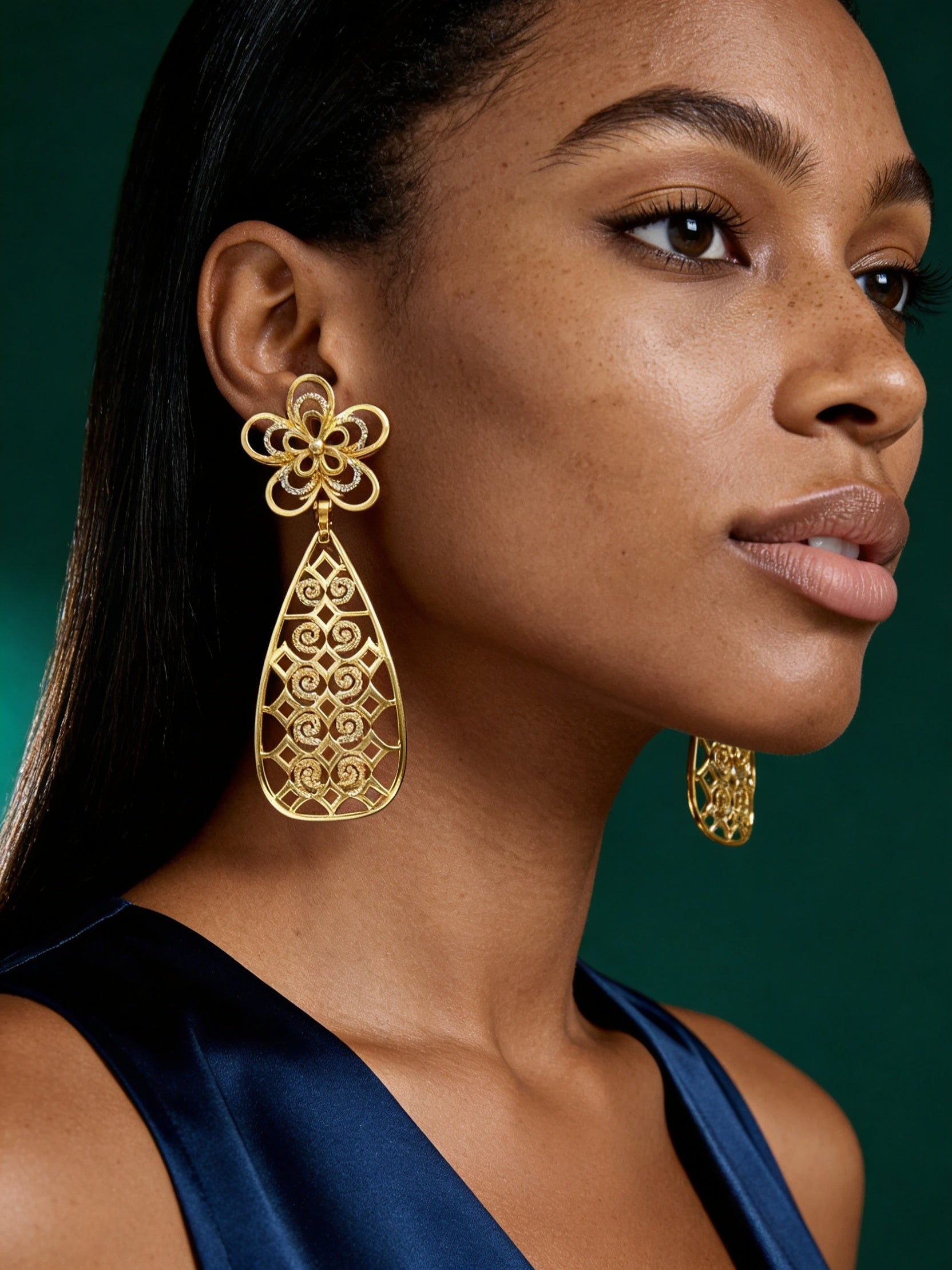 Model wearing luxurious African-inspired floral gold drop earrings with sculptural hollow teardrop design for an elegant statement look.
