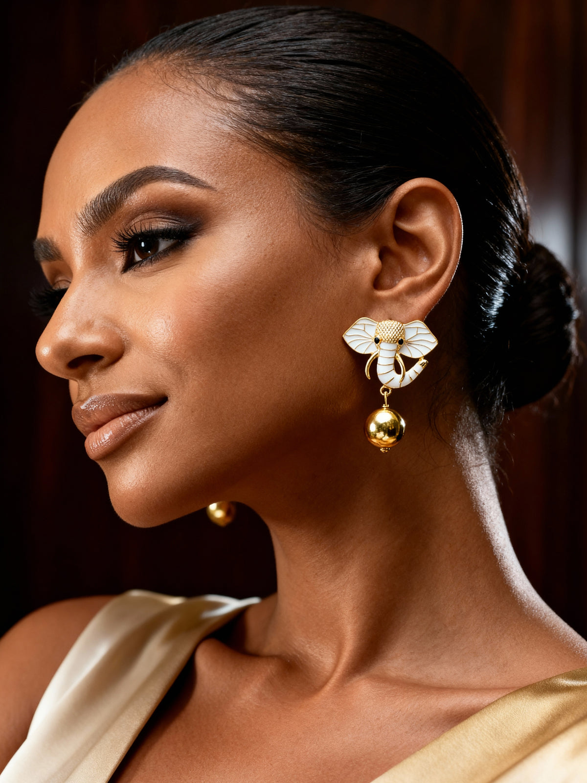 Dainty gold elephant earrings styled with neutral fashion, showcasing meaningful animal-inspired jewelry with a modern finish.