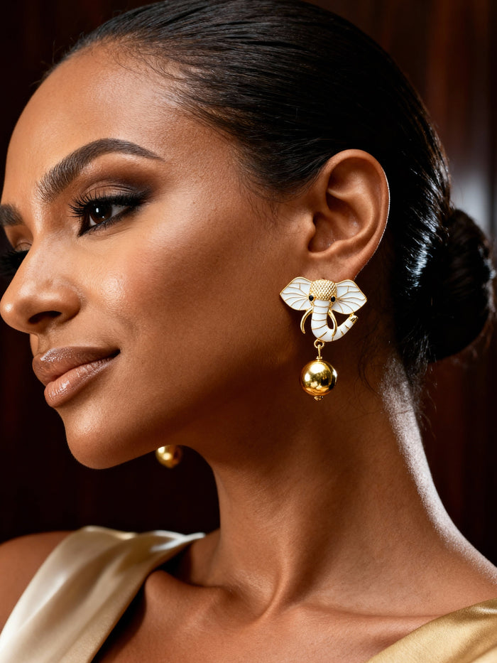 Dainty gold elephant earrings styled with neutral fashion, showcasing meaningful animal-inspired jewelry with a modern finish.