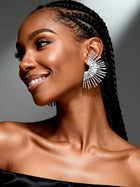 Model wearing oversized silver sunburst stud earrings with a bold sculptural fan design, styled for modern everyday luxury.