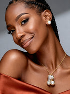 Woman wearing a delicate gold pearl peanut pendant necklace with a satin off-the-shoulder dress, showcasing elegant nature-inspired jewellery for weddings, anniversaries, and special occasions